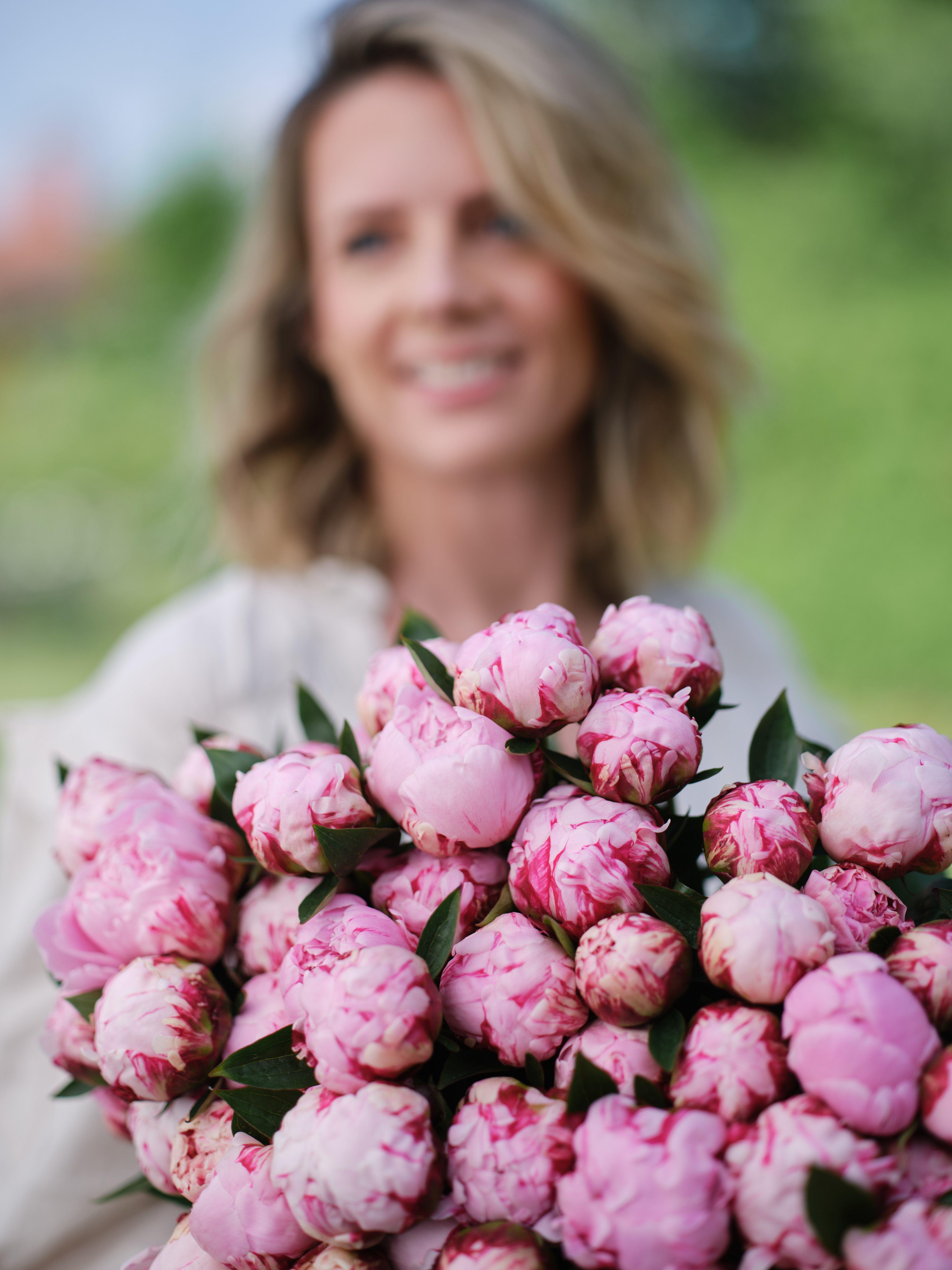 Dame med stor bukett rosa peoner