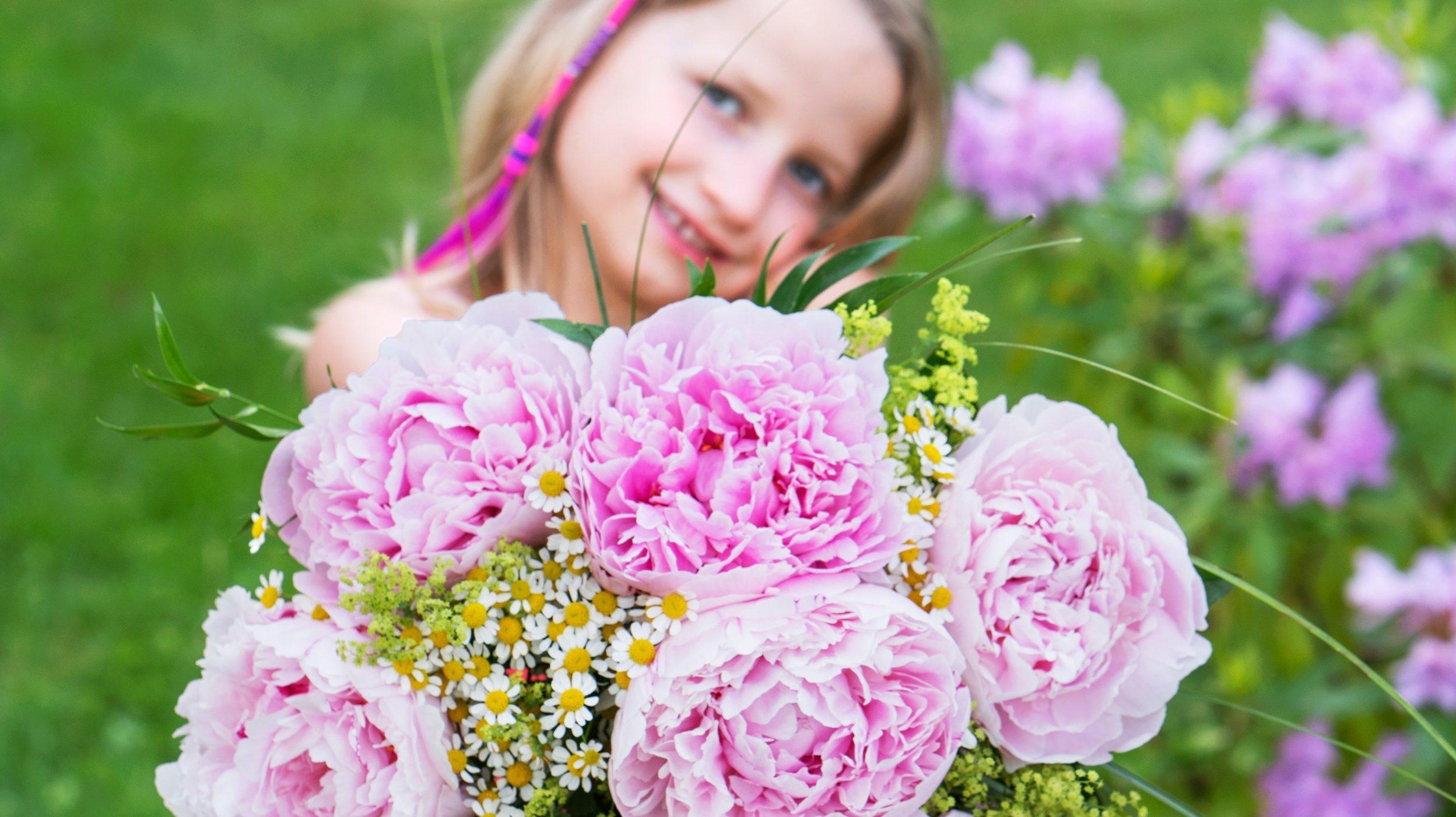 Jente i hage med rosa silkepeoner