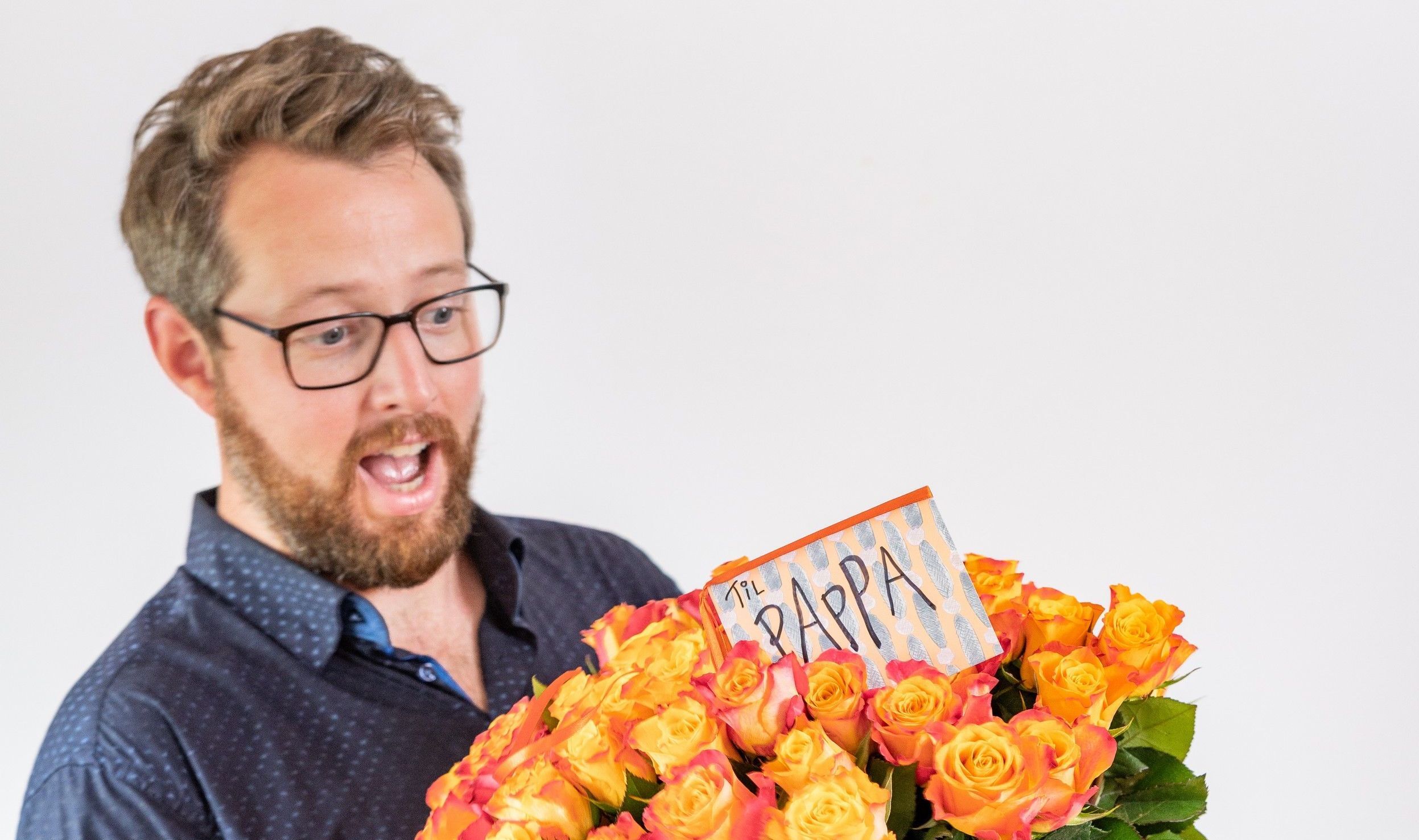 Glad pappa som får oransje roser